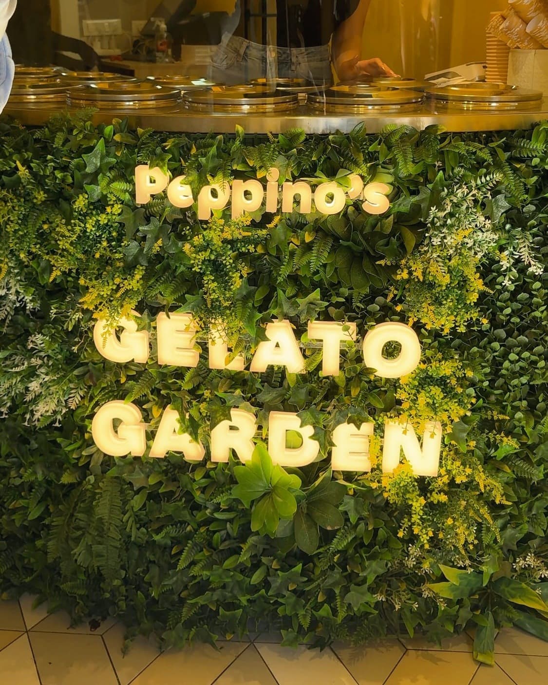 The Peppino's Gelato Garden sign in lights on a hedge wall