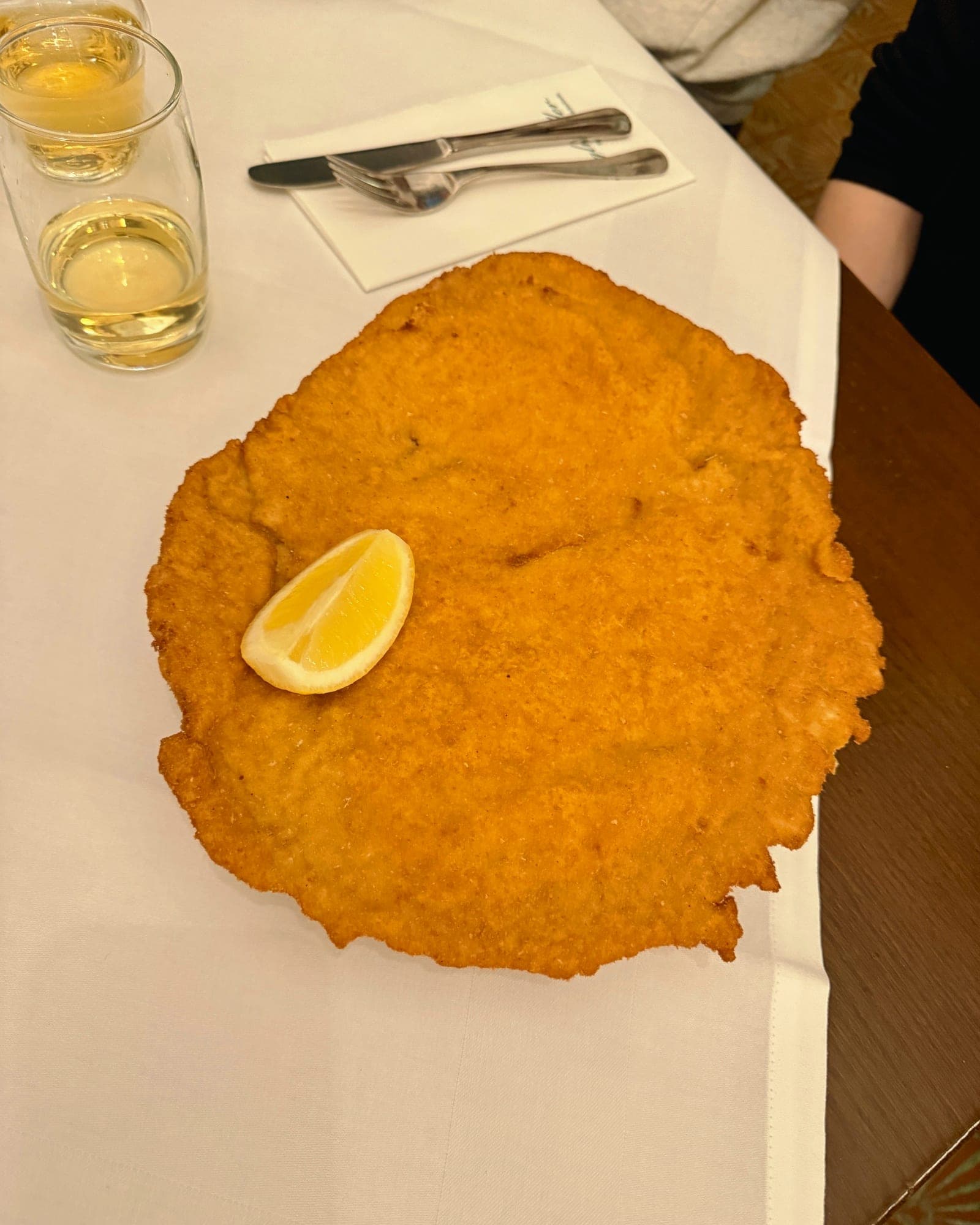 A Figlmüller schnitzel covering the whole plate, with a lemon wedge