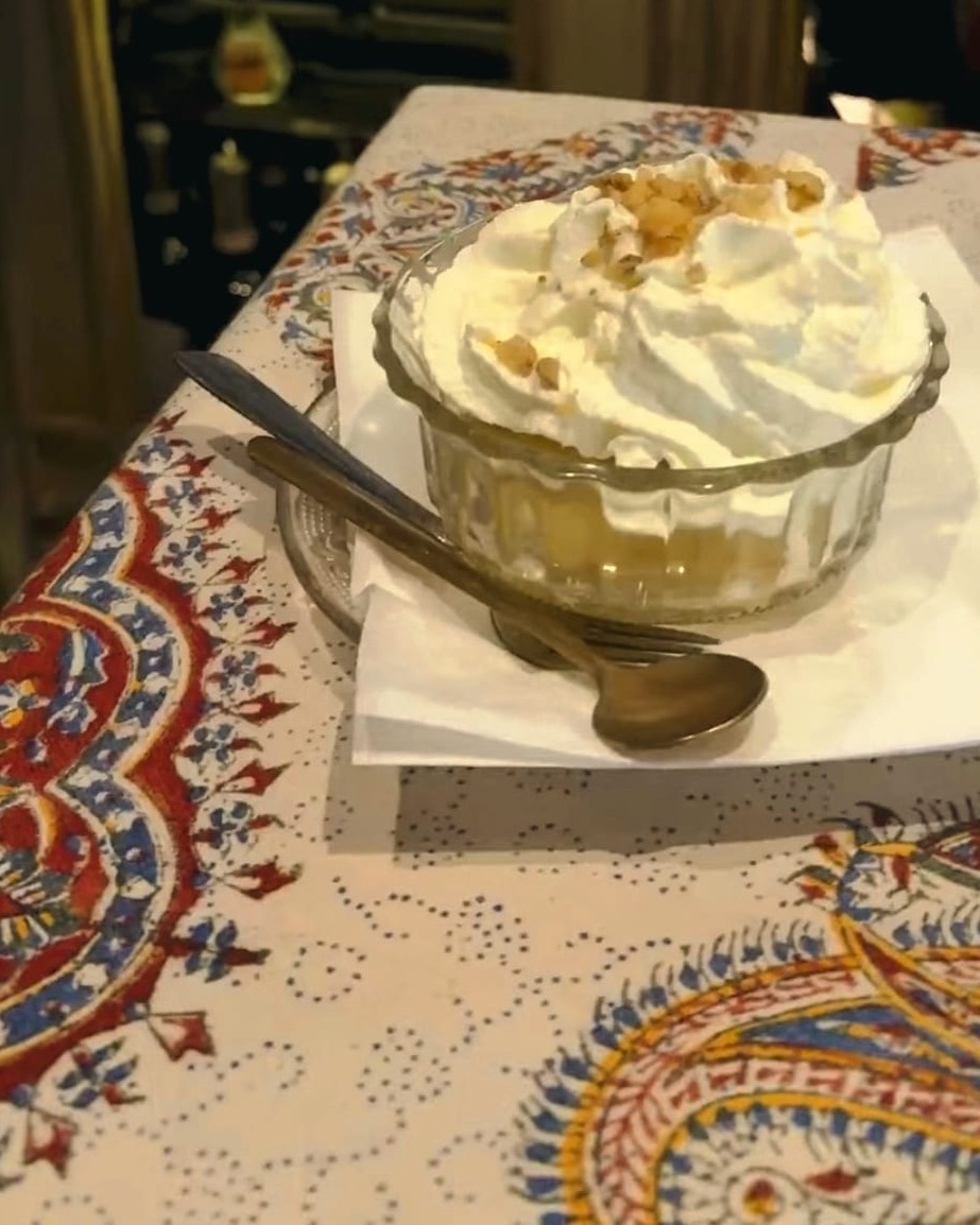Tufahija: a poached apple under whipped cream in a silver dish